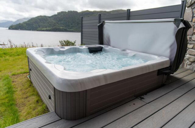 A Platinum Spas hot tub at a holiday let in Scotland. The hot tub is located next to some decking and next to a large lake.
