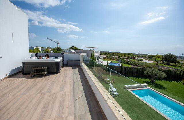 A Platinum Spas hot tub on a terrace in Spain. There is a swimming pool below the terrace.