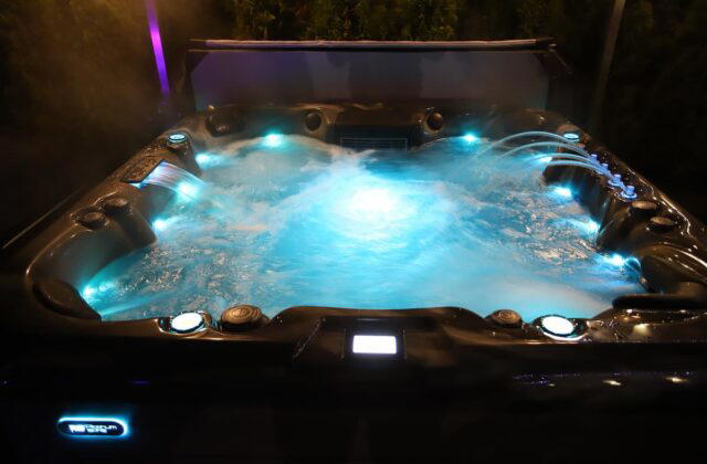 A Platinum Spas hot tub lit by mood lighting at night.