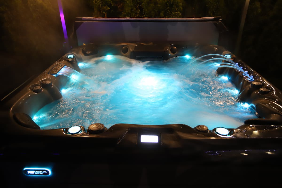 A Platinum Spas hot tub lit by mood lighting at night.