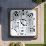 Overhead view of a Platinum Spas Barcelona hot tub on a garden patio, showing the two loungers, three seats and 86 jets