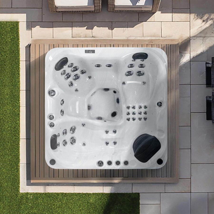 Overhead view of a Platinum Spas Happy hot tub on a paved patio with loungers and rattan chairs nearby