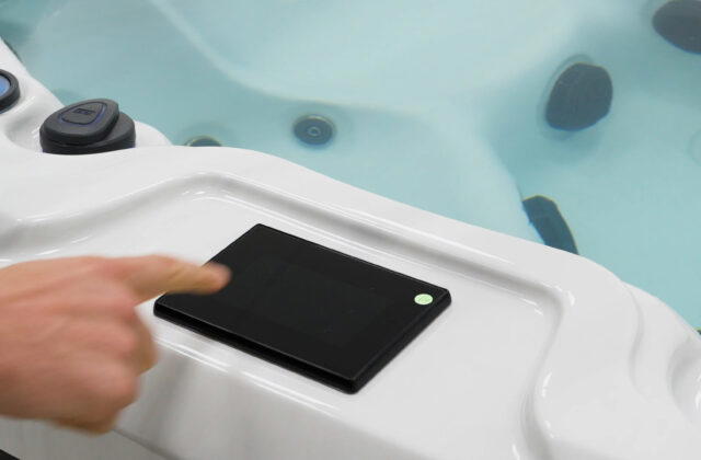 Finger reaching for the SpaTouch touchscreen control panel on a Platinum Spas hot tub
