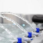 Close-up of arching cascade water jets on a Platinum Spas Refresh hot tub, lit by blue LEDs