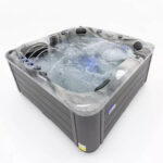 Platinum Spas Refresh hot tub filled and running, showing the cascading water feature and blue LED lighting