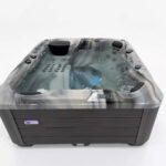 Platinum Spas Refresh hot tub filled and running, with bubbling jets and a cascading water feature lit by blue LEDs