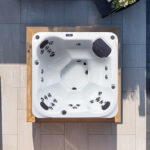 Draufsicht auf einen Platinum Spas St Tropez Whirlpool auf einer gepflasterten Terrasse mit Sitzanordnung und Düsen