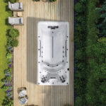 Platinum Spas Eros swim spa overhead view on a wooden deck surrounded by garden and loungers