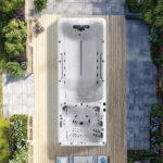 Platinum Spas Helios swim spa overhead view installed on a wooden deck surrounded by garden landscaping