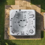 Overhead view of a Platinum Spas Positano hot tub on a paved patio, showing all four seats, the lounger and jet layout