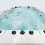 Platinum Spas Titan swim spa filled with water showing cascading waterfall jets and illuminated corner seating