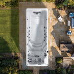 Platinum Spas Zelus swim spa overhead view installed on a stone patio surrounded by garden and outdoor seating