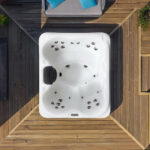 Overhead view of a Platinum Spas Vacation Retreat hot tub on a decked patio, showing jets, headrest and loungers