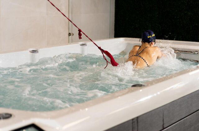 Swimmer training against a tether in a Platinum Spas Helios swim spa