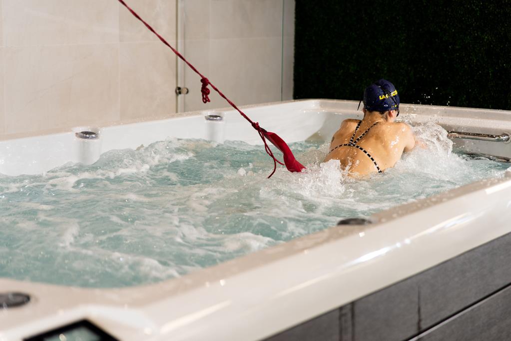 Swimmer training against a tether in a Platinum Spas Helios swim spa